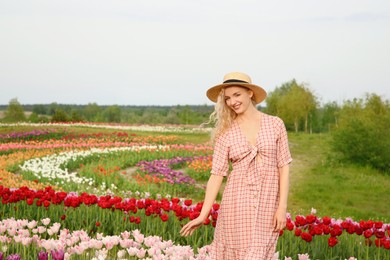 Photo of Happy woman in beautiful tulip field outdoors