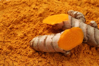 Photo of Cut raw root on aromatic turmeric powder, closeup