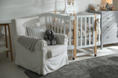 Photo of Baby room interior with crib and armchair. Idea for design