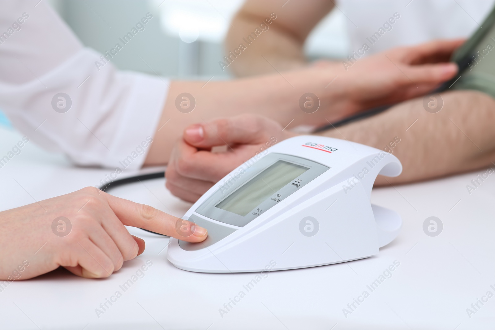 Photo of Doctor checking blood pressure of man in clinic, closeup