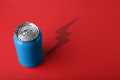 Energy drink and shadow in shape of lightning on red background 