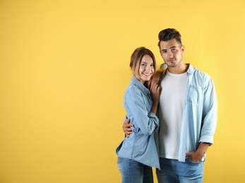 Photo of Young couple in stylish clothes on color background. T-shirts as mockup for design