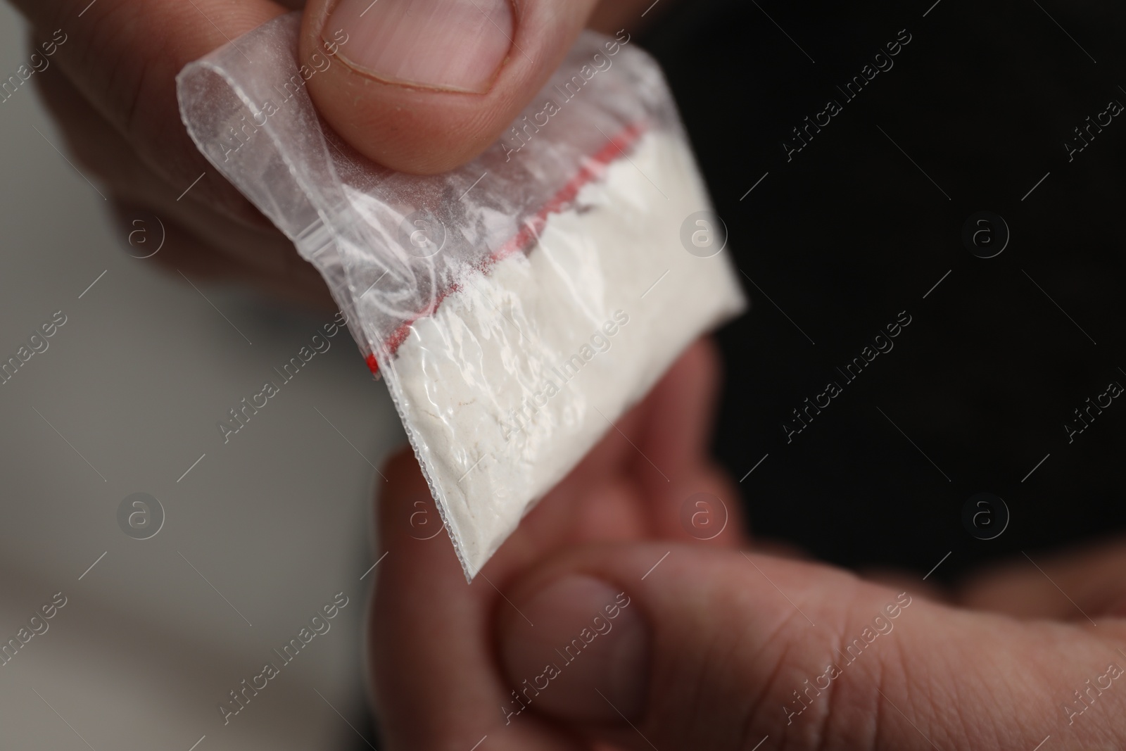 Photo of Drug addiction. Man with plastic bag of cocaine on light background, closeup