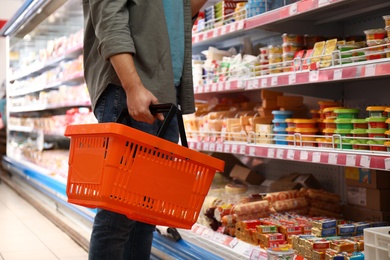 Man with shopping basket in supermarket, closeup