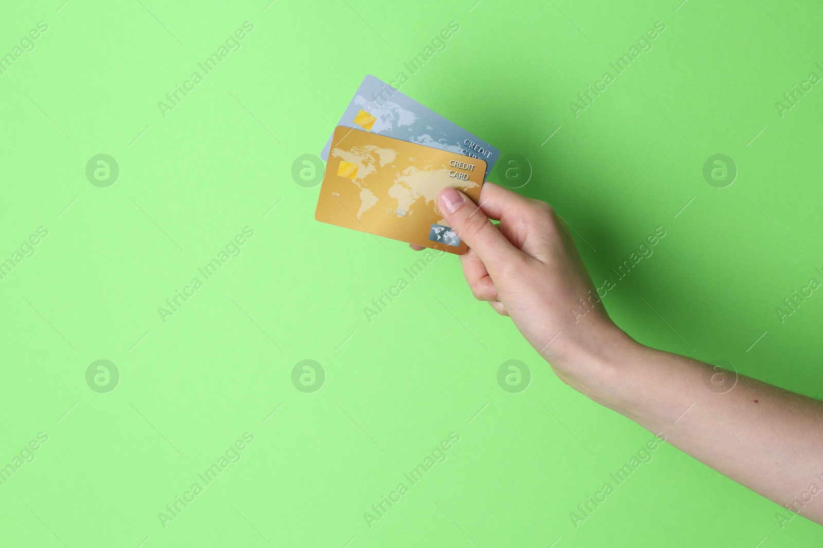 Photo of Woman holding credit cards on light green background, closeup