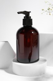 Bottle of shampoo on podium against white background