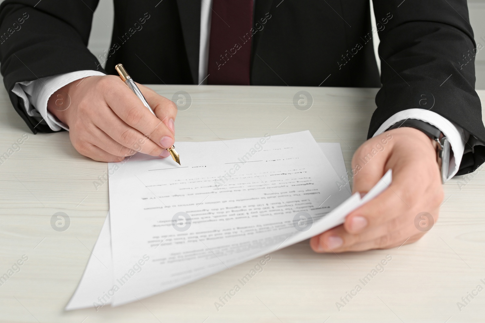 Photo of Notary signing document at wooden table, closeup