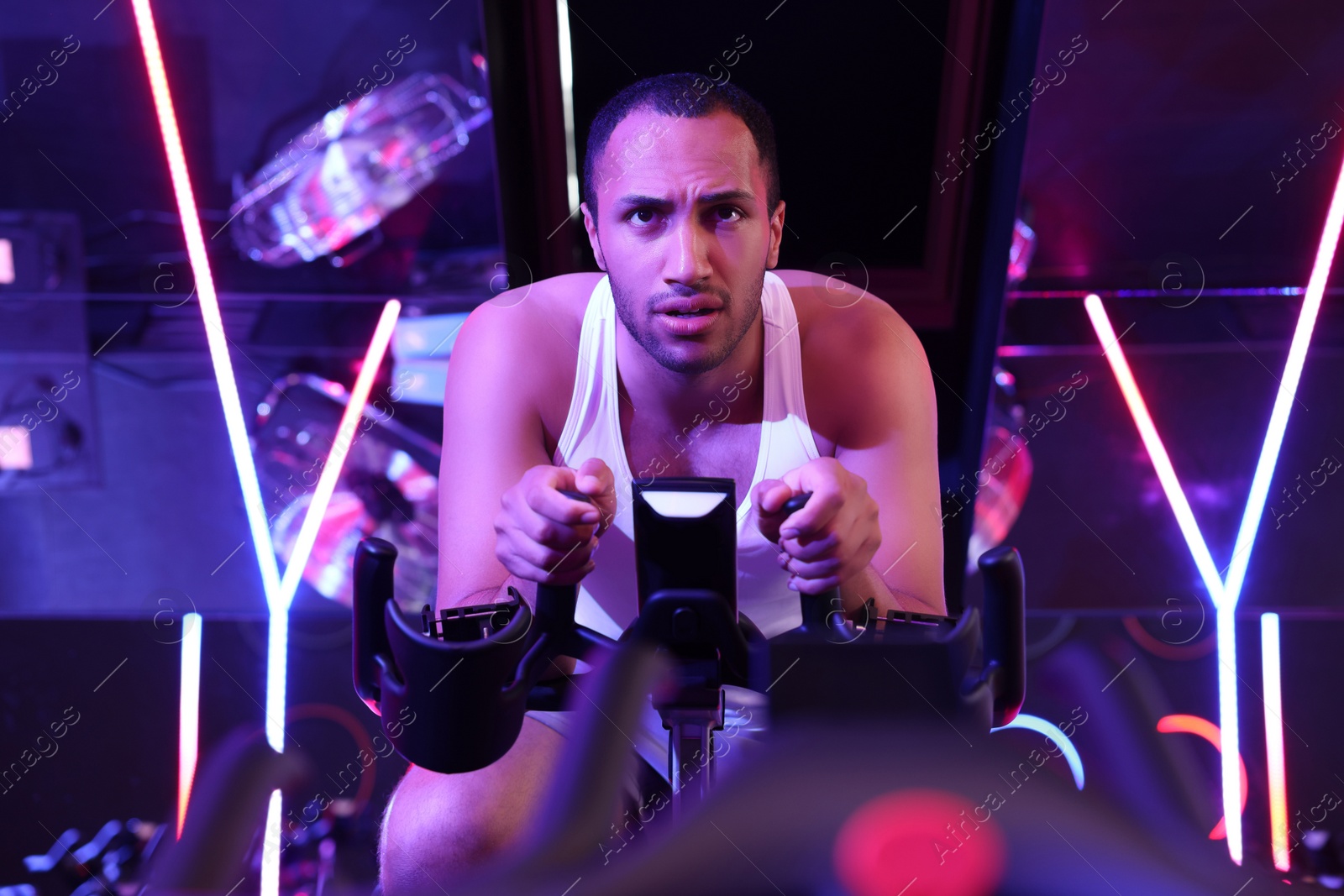 Photo of Young man training on exercise bike in fitness club