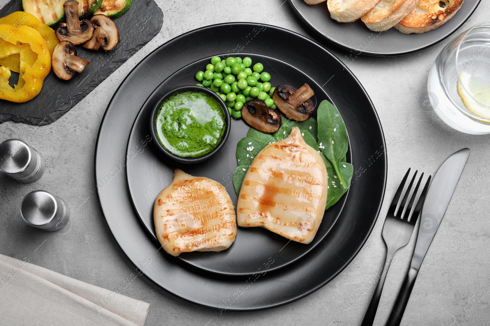 Photo of Grilled squid tubes served on grey table, flat lay