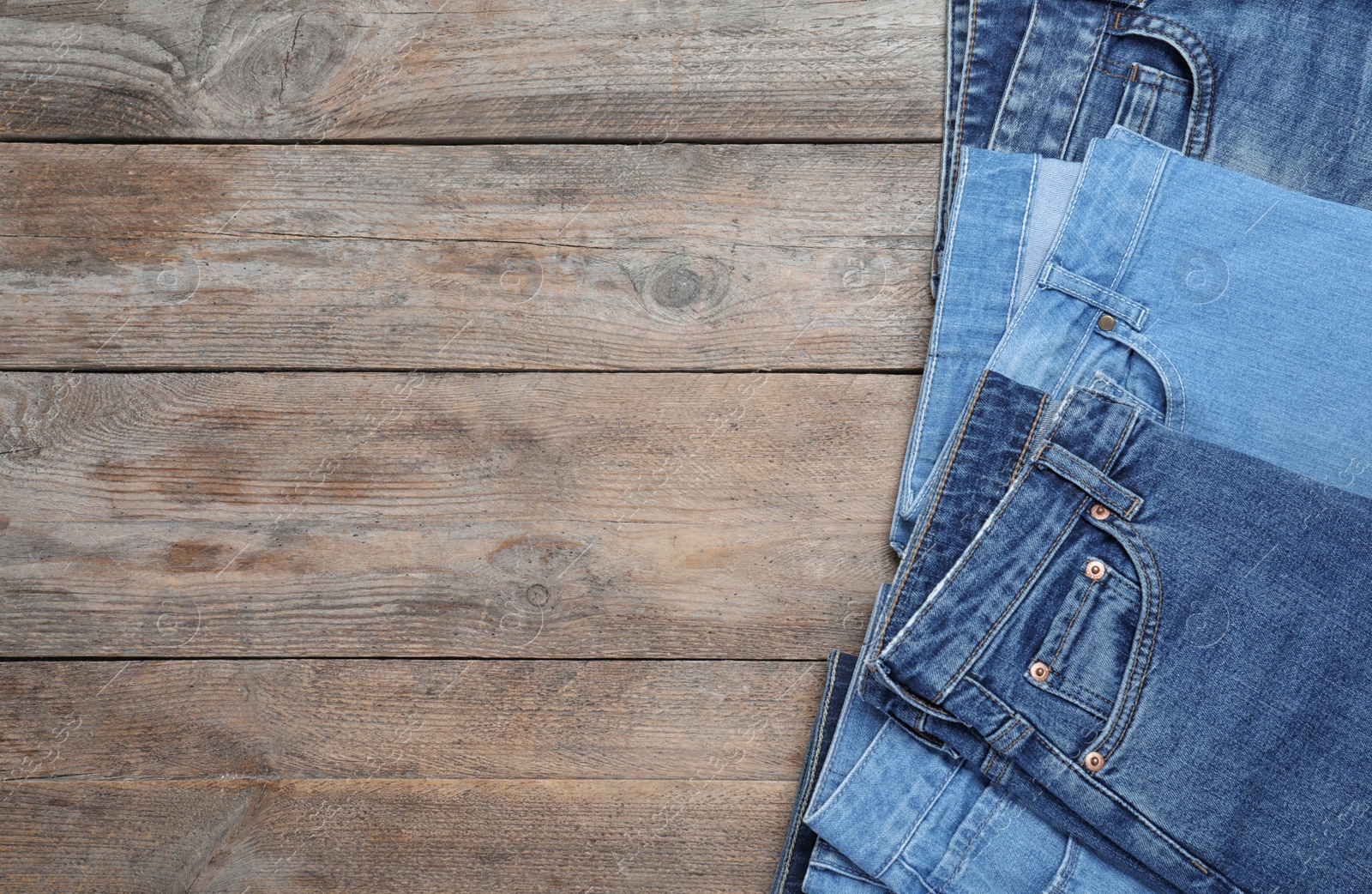 Photo of Collection of stylish jeans on wooden background, flat lay. Space for text