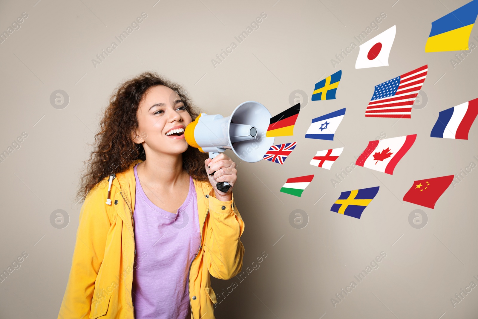 Image of Portrait of African American interpreter with megaphone and flags of different countries on beige background