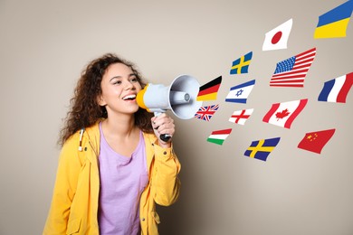 Image of Portrait of African American interpreter with megaphone and flags of different countries on beige background