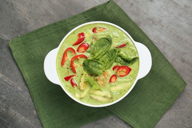 Photo of Saucepan with delicious green curry chicken soup on light grey table, top view