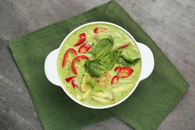 Saucepan with delicious green curry chicken soup on light grey table, top view