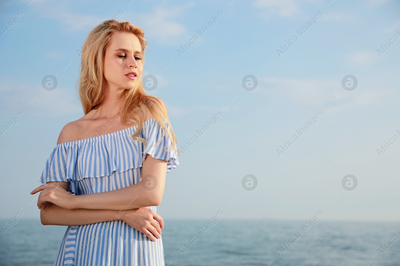 Photo of Beautiful young woman near sea on sunny day, space for text