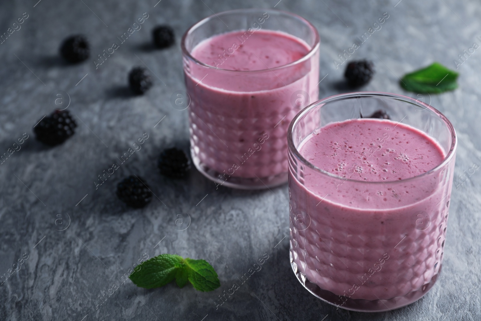 Photo of Glasses with tasty blackberry yogurt smoothies on grey table