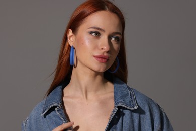 Photo of Beautiful young woman in denim jacket on gray background