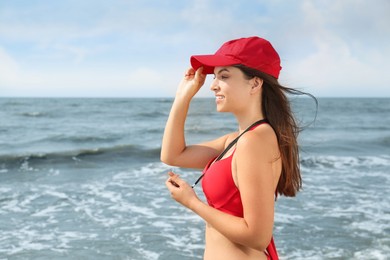 Photo of Beautiful young lifeguard with whistle near sea