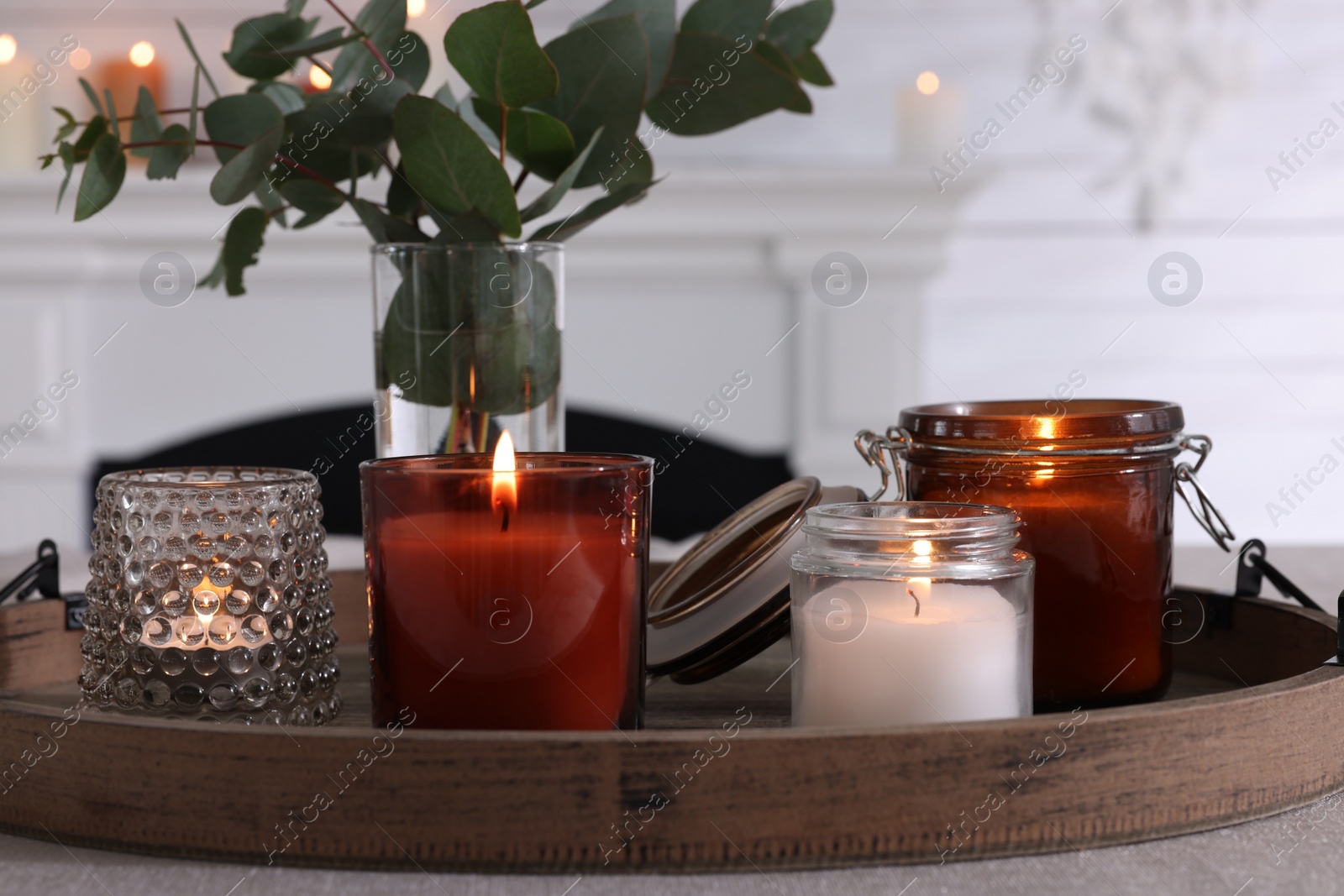 Photo of Tray with beautiful burning candles and vase on table indoors