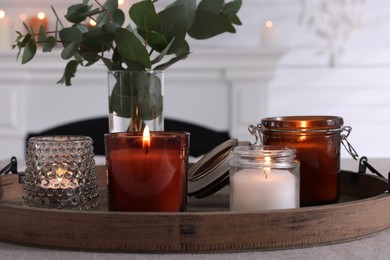 Photo of Tray with beautiful burning candles and vase on table indoors