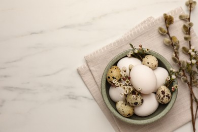 Easter eggs, flowers and pussy willow branches on white marble table, top view. Space for text