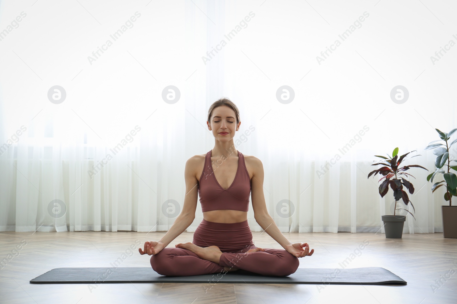 Photo of Young woman practicing lotus asana in yoga studio. Padmasana pose