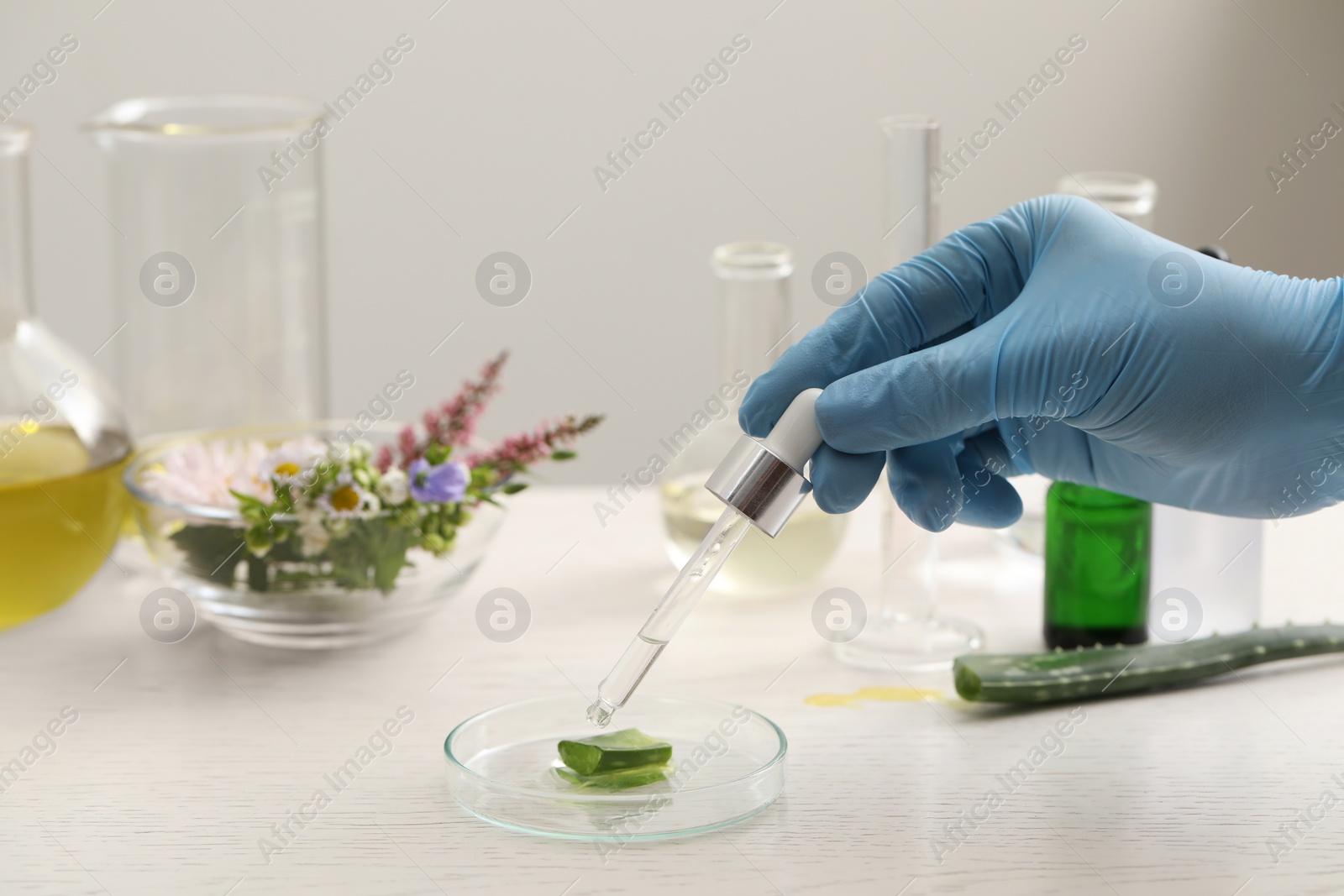 Photo of Scientist developing cosmetic oil at white table, closeup