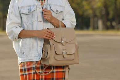 Young woman with stylish beige backpack on city street, closeup