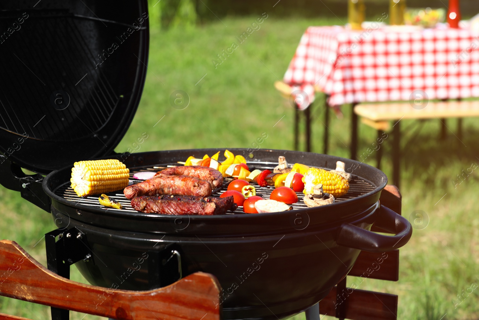 Photo of Tasty steak, sausages and vegetables on modern barbecue grill outdoors