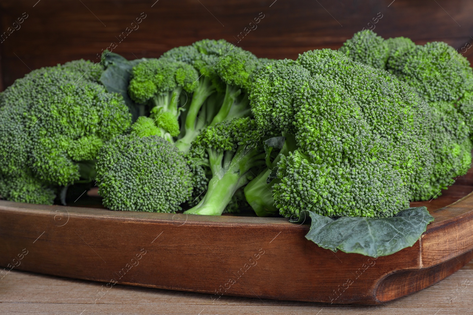 Photo of Tray with fresh raw broccoli on wooden table, closeup