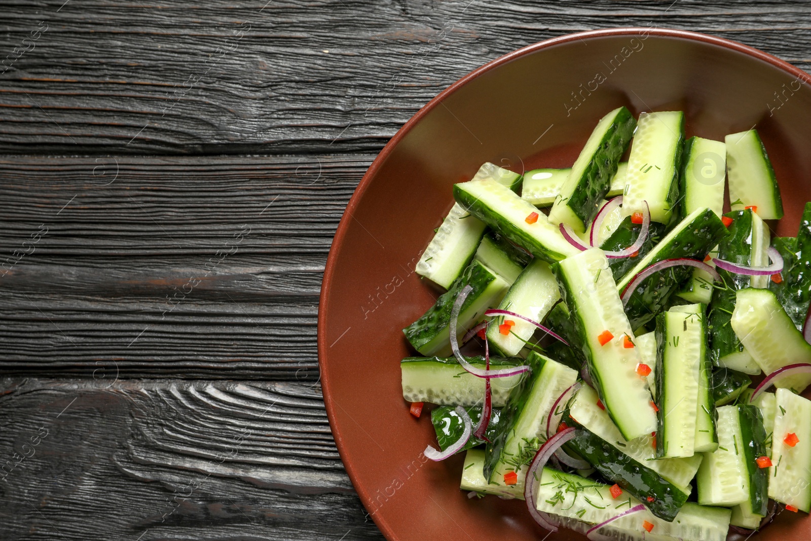 Photo of Plate with delicious cucumber salad on wooden background, top view. Space for text