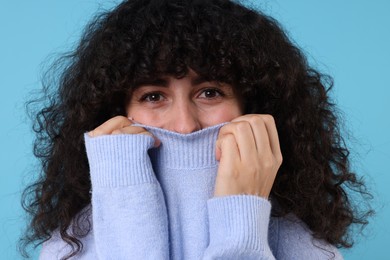 Photo of Young woman in stylish warm sweater on light blue background
