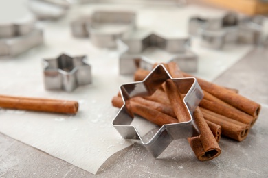 Cutters and cinnamon sticks for Christmas cookies on table