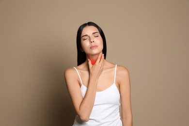 Image of Young woman doing thyroid self examination on beige background