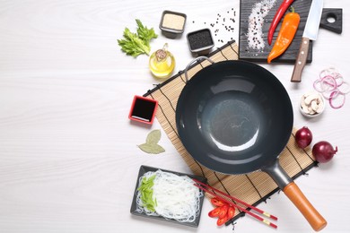 Photo of Wok, chopsticks and different products on white wooden table, flat lay. Space for text