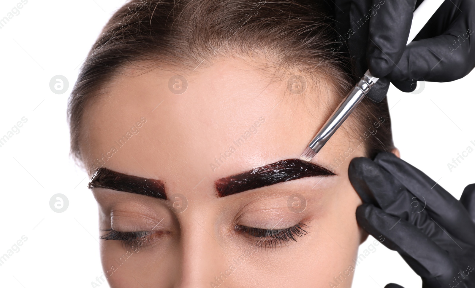 Photo of Beautician applying tint during eyebrows correction procedure on white background, closeup