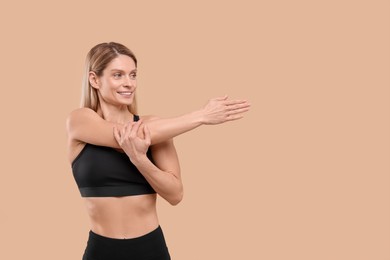 Photo of Athletic woman stretching on beige background, space for text