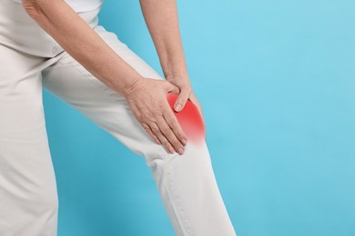 Image of Woman suffering from pain in knee on light blue background, closeup. Space for text