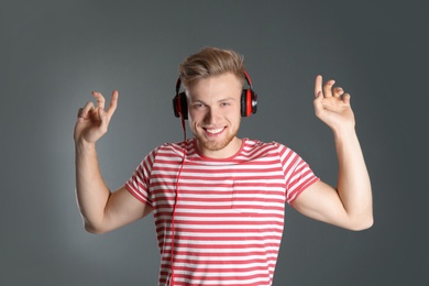 Photo of Handsome young man listening to music with headphones on color background