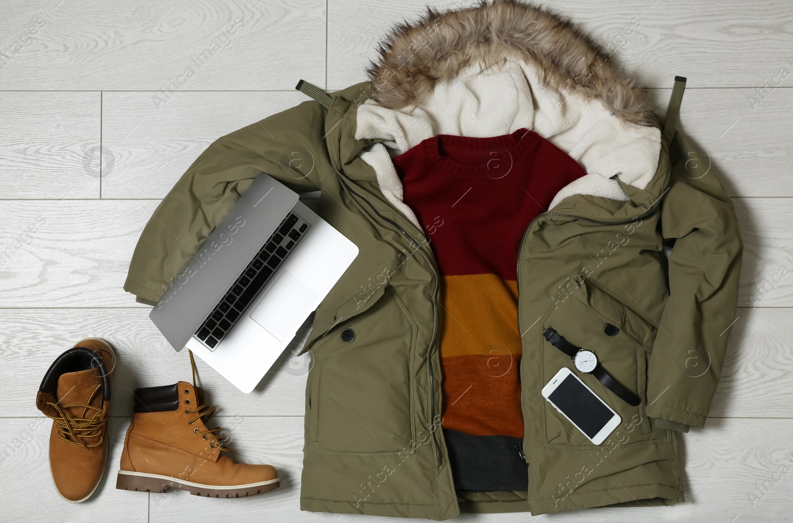 Photo of Set of warm clothes and devices on wooden background, flat lay. Winter vacation