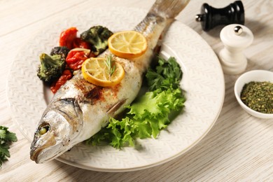 Photo of Delicious baked fish and vegetables served on wooden table, closeup