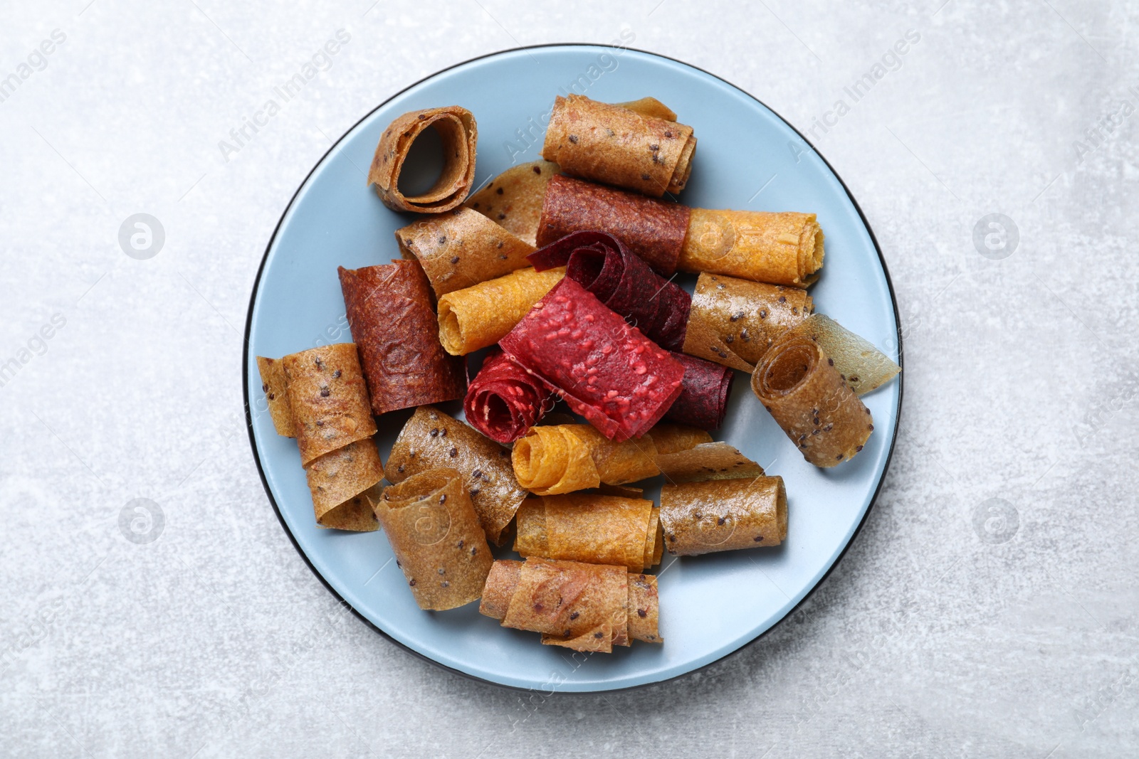 Photo of Delicious fruit leather rolls on grey table, top view