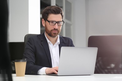 Photo of Man working on laptop at white desk in office