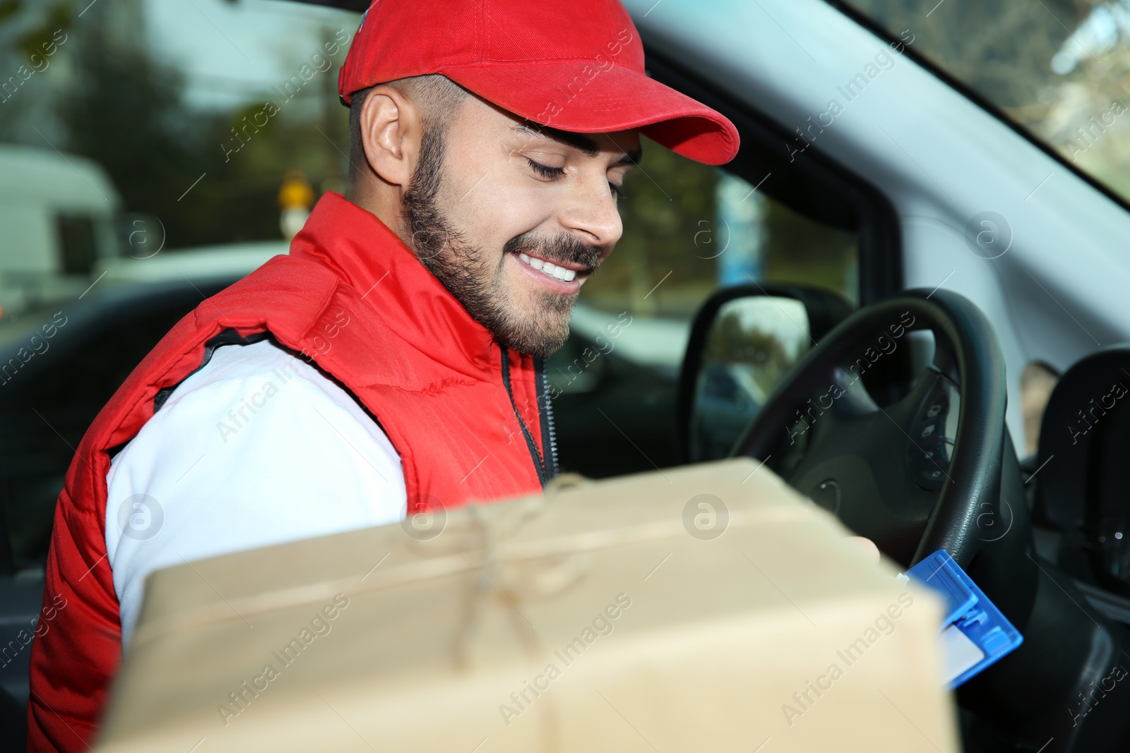 Photo of Young courier checking amount of parcels in delivery van