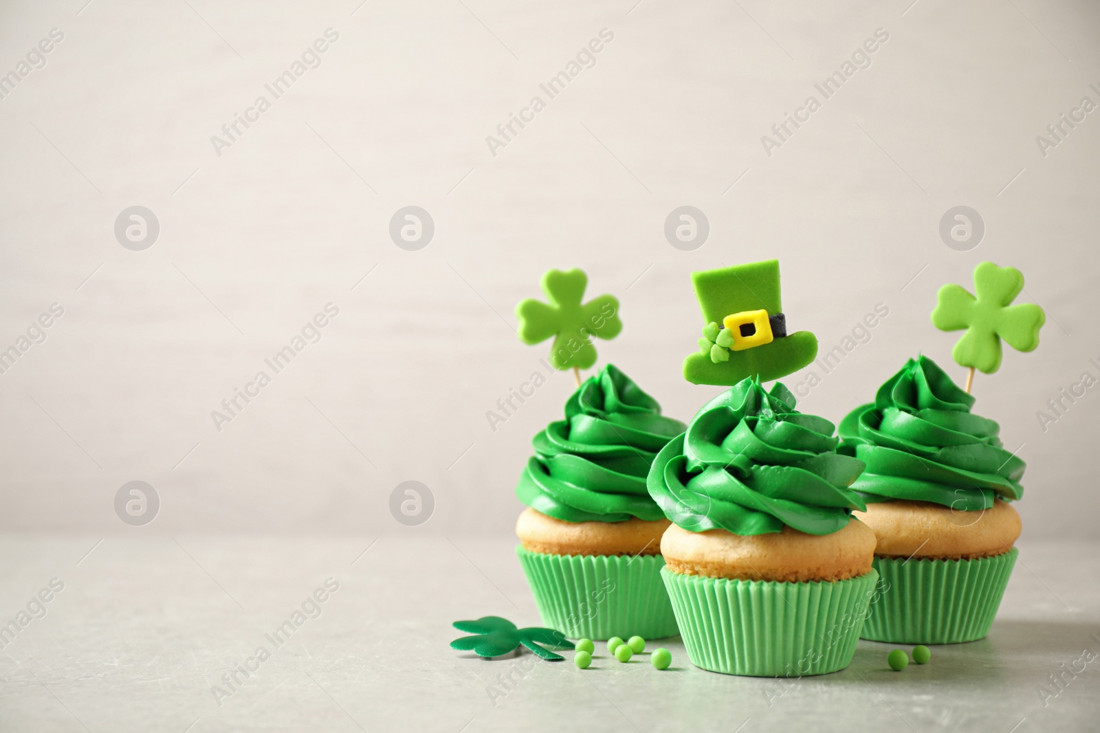 Photo of Delicious decorated cupcakes on light table, space for text. St. Patrick's Day celebration