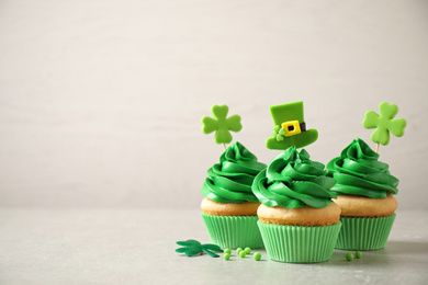 Photo of Delicious decorated cupcakes on light table, space for text. St. Patrick's Day celebration