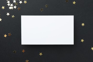 Blank business card and confetti on black background, top view. Mockup for design