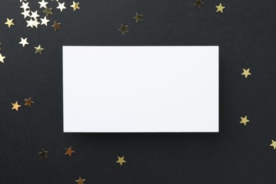 Photo of Blank business card and confetti on black background, top view. Mockup for design