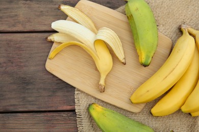 Photo of Whole and cut bananas on wooden table, flat lay. Space for text