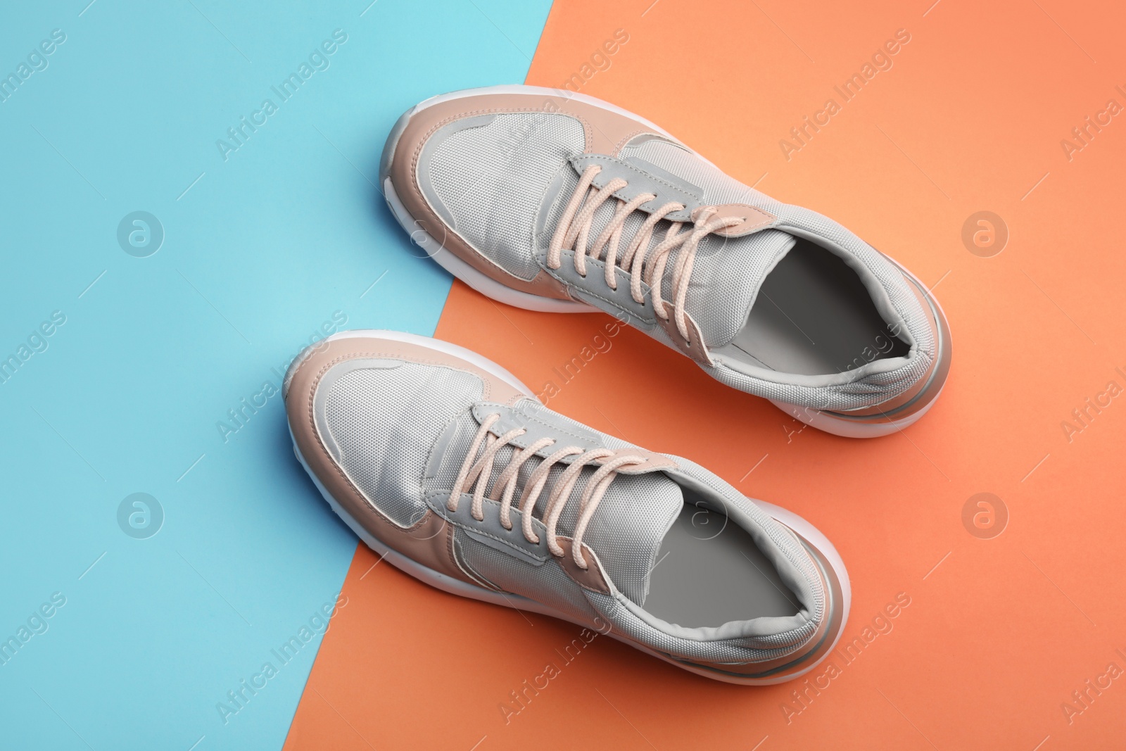 Photo of Grey and coral female sneakers on color background, top view